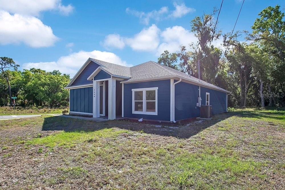 A blue, single-story house with a gabled roof sits on a grassy lot — 2498 MITCHELL AVENUE, MIMS, FL