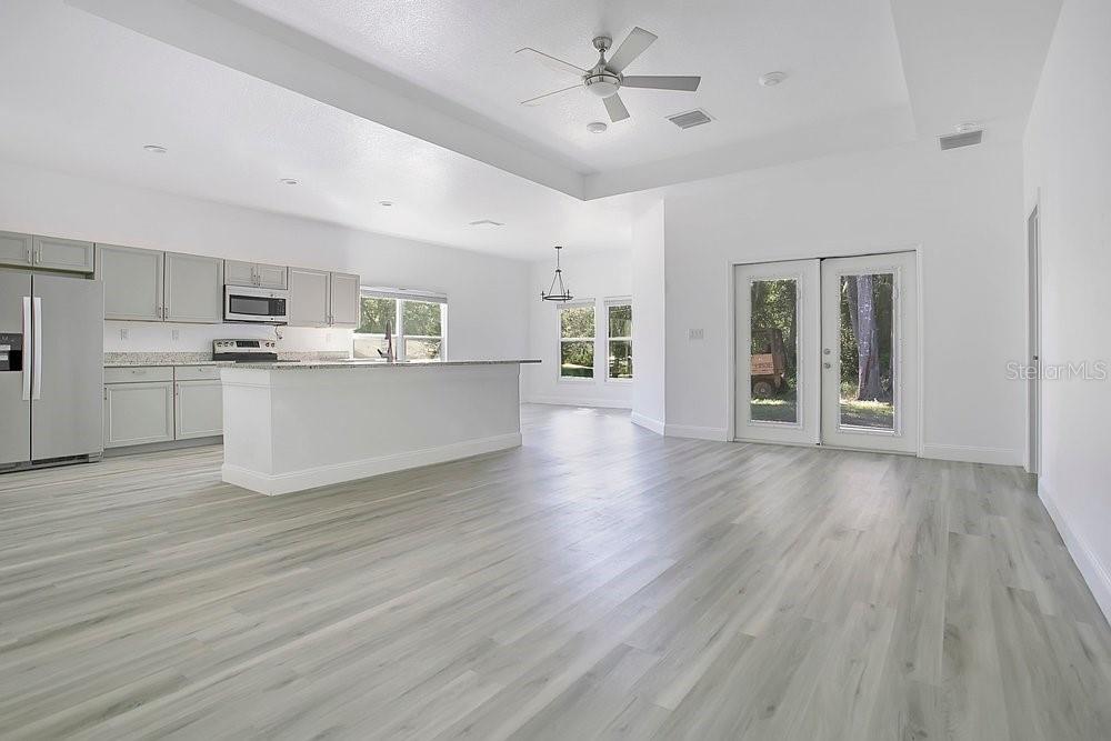 An open-concept kitchen and living area with light wood flooring and white cabinetry — 2498 MITCHELL AVENUE, MIMS, FL