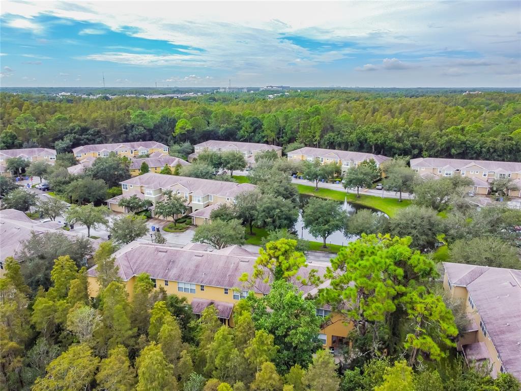 An aerial view of a yellow multi-unit townhouse with a shingled roof and garages — 8116 STONE PATH WAY, TAMPA, FL