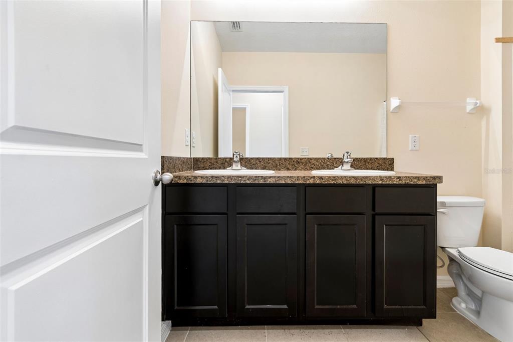 A bathroom features a dark wood double vanity with a granite countertop and large mirror — 11181 LELAND GROVES DRIVE, RIVERVIEW, FL