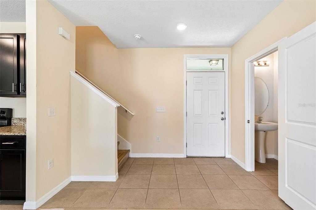 An entryway features beige tile flooring, a staircase, a front door, and a half bathroom — 11181 LELAND GROVES DRIVE, RIVERVIEW, FL