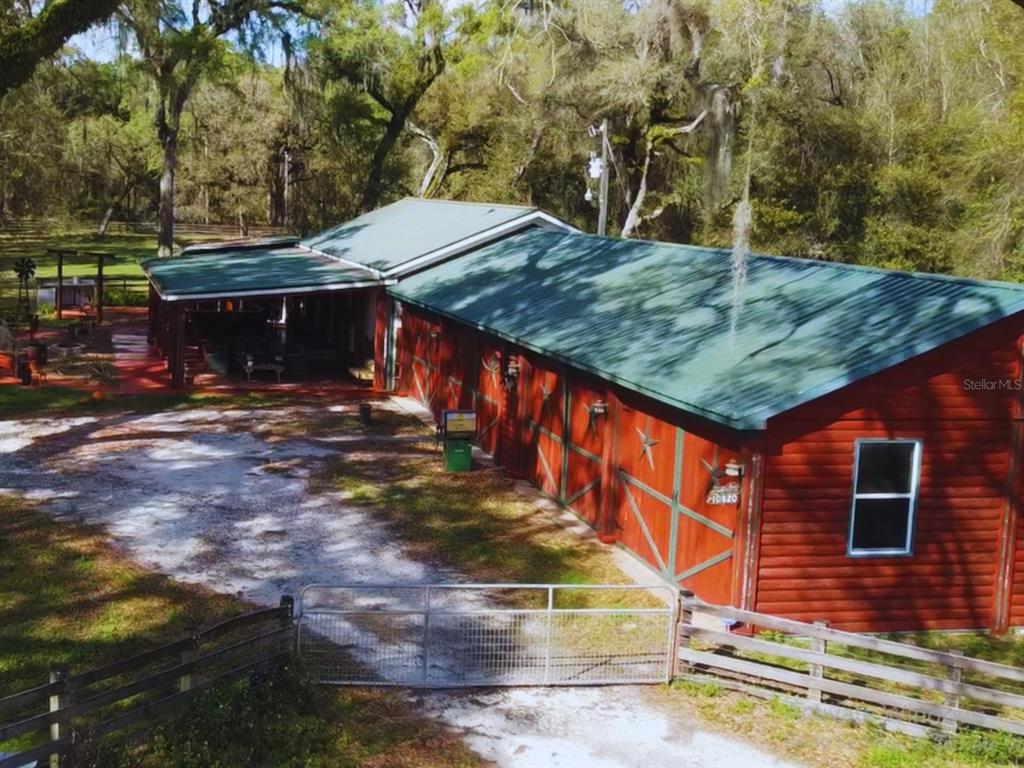 An aerial view of a red barn-style building with a green metal roof and porch — 10820 SW 31ST WAY, WEBSTER, FL