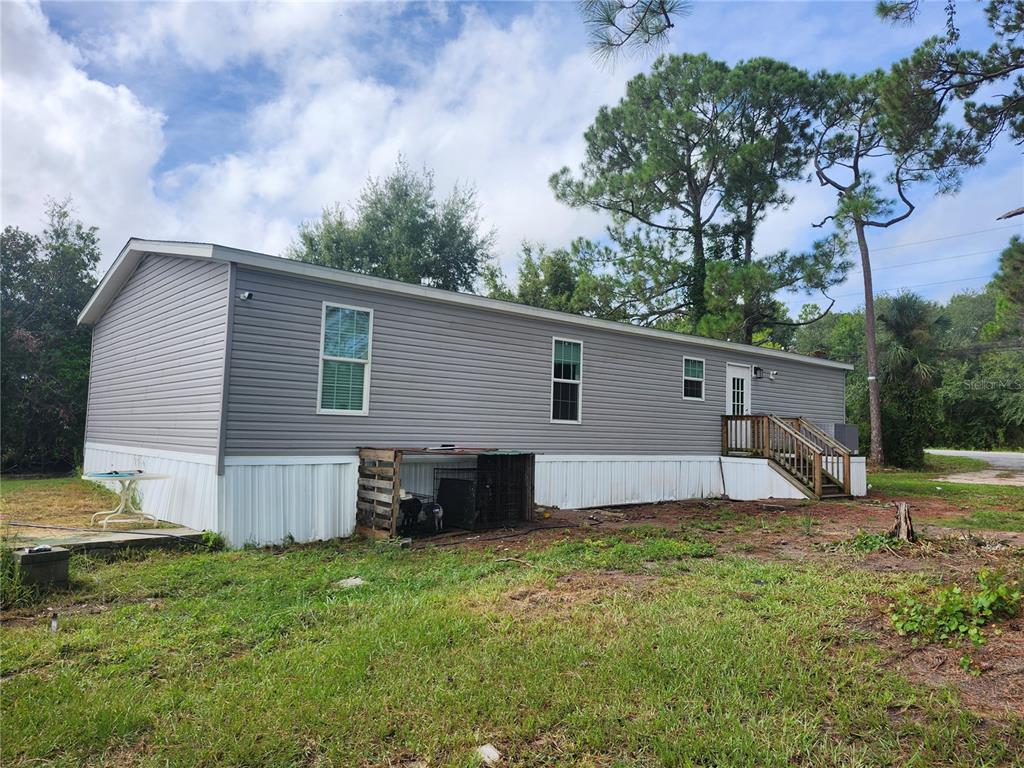 The exterior of a gray manufactured home features white skirting, a wooden staircase, and a yard — 4550 POLK CITY ROAD, HAINES CITY, FL