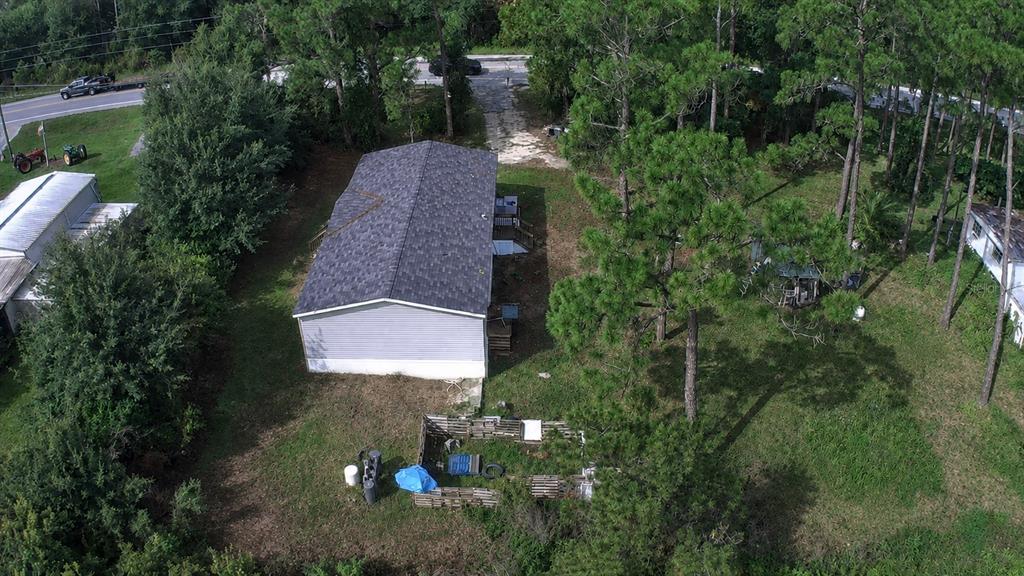 An aerial view shows a house with a gray roof situated near a body of water — 4550 POLK CITY ROAD, HAINES CITY, FL