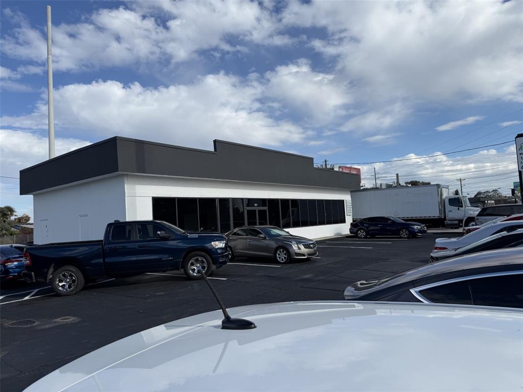 A modern commercial building with a dark gray facade and white walls sits in a parking lot — 5005 EDGEWATER DRIVE, ORLANDO, FL