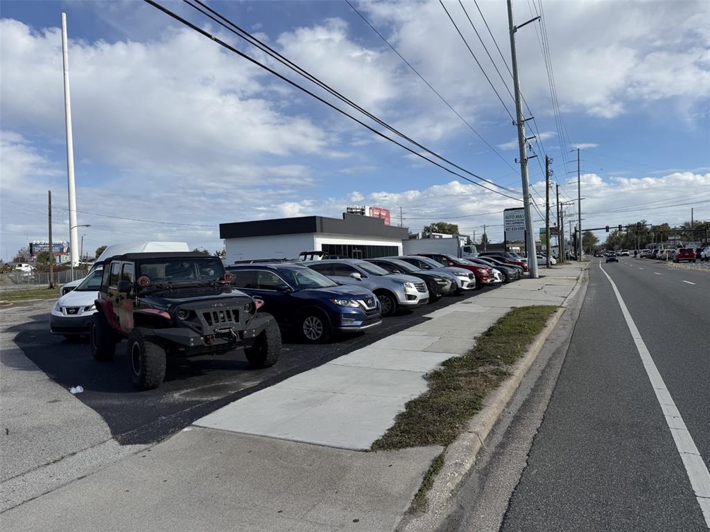 A row of cars is parked in a lot next to a commercial building — 5005 EDGEWATER DRIVE, ORLANDO, FL