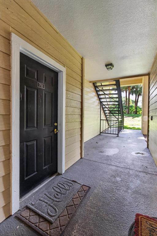 An exterior view of an apartment entrance with a black door, stairs, and concrete flooring — 2612 ROBERT TRENT JONES DRIVE UNIT 711, ORLANDO, FL