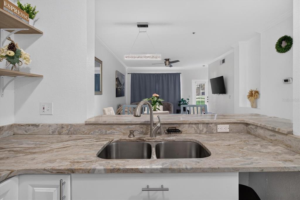 A kitchen sink with granite countertops overlooks an open-concept living and dining area — 2612 ROBERT TRENT JONES DRIVE UNIT 711, ORLANDO, FL