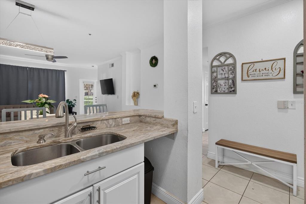 A kitchen sink with granite countertops overlooks a living area with a dining table — 2612 ROBERT TRENT JONES DRIVE UNIT 711, ORLANDO, FL