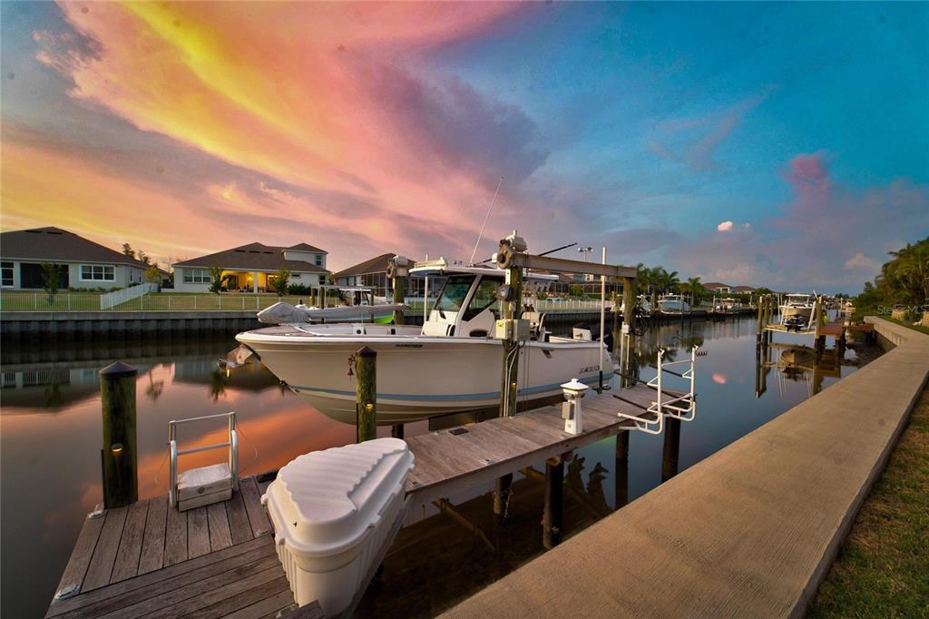 A boat is docked at a wooden pier on a canal at sunset — 713 ISLEBAY DRIVE, APOLLO BEACH, FL