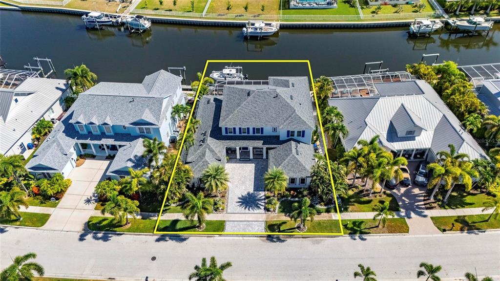 An aerial view shows a waterfront house with a gray roof and a paved driveway — 713 ISLEBAY DRIVE, APOLLO BEACH, FL