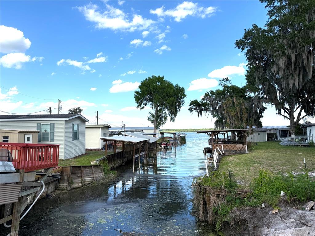 A canal leads from a residential shoreline toward a large lake under a blue sky — 748 CR 477A, LAKE PANASOFFKEE, FL