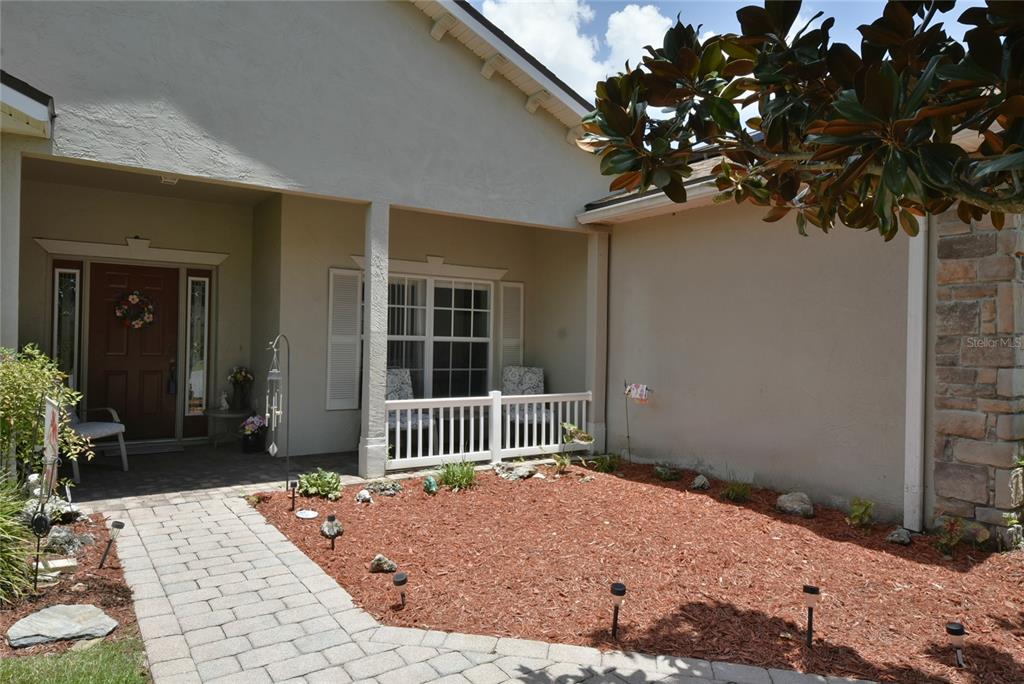 A paved walkway leads to a covered front porch with a white railing and door — 4360 ASHTON CLUB DRIVE, LAKE WALES, FL