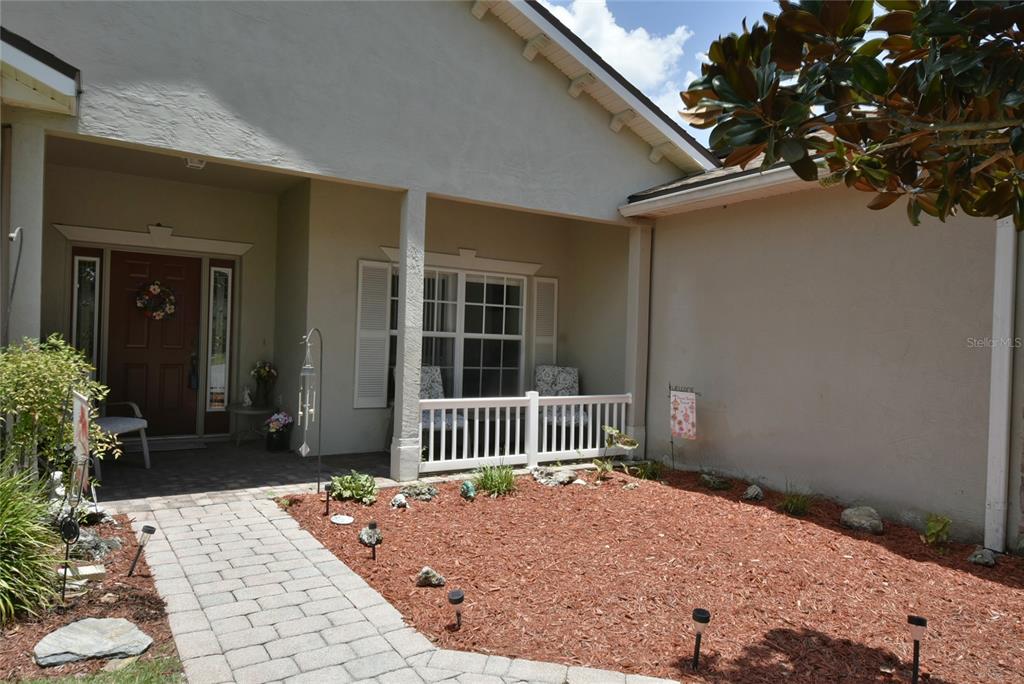 A paved walkway leads to a covered front porch with a white railing and entryway — 4360 ASHTON CLUB DRIVE, LAKE WALES, FL