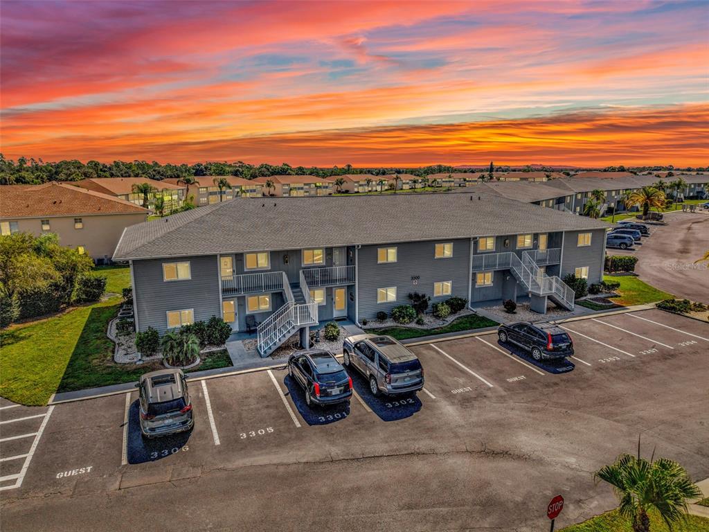An exterior view of a two-story apartment building with a parking lot at sunset — 12274 SW EGRET CIRCLE UNIT 3302, LAKE SUZY, FL