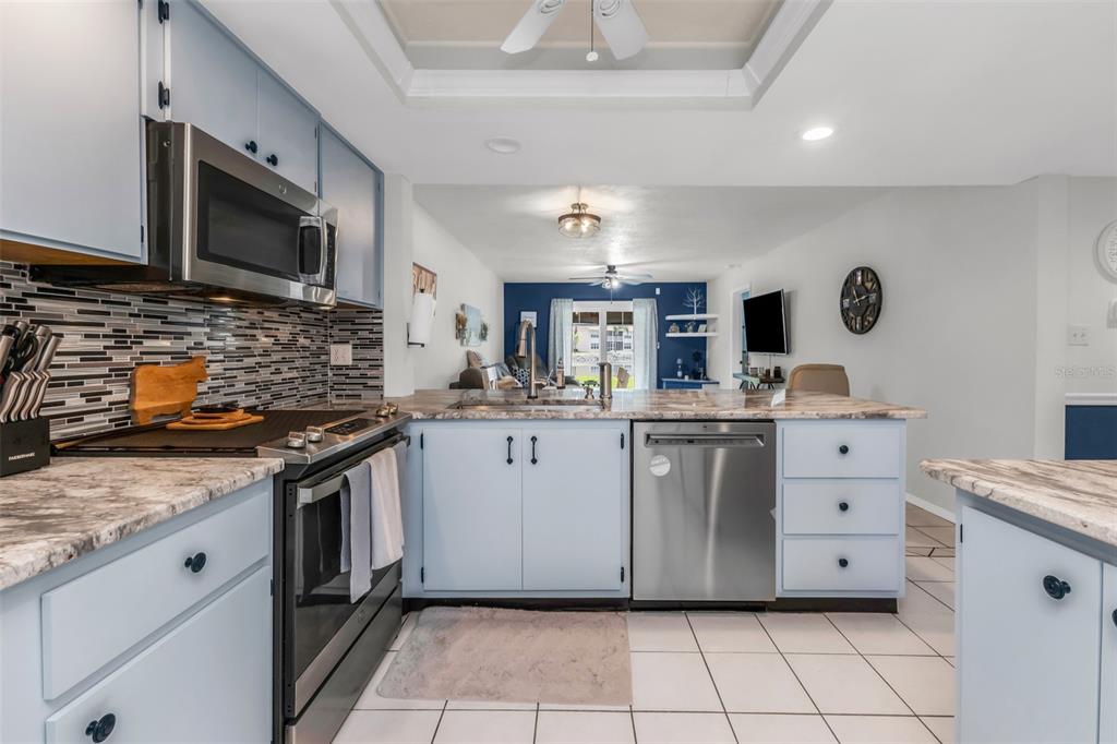 A kitchen with light blue cabinets, stainless steel appliances, and a granite countertop island — 12274 SW EGRET CIRCLE UNIT 3302, LAKE SUZY, FL