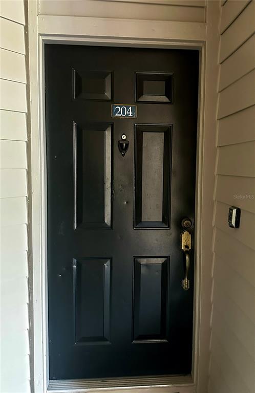 A black front door with the number 204 mounted on it in a recessed entryway — 420 SUMMIT RIDGE PLACE UNIT 204, LONGWOOD, FL