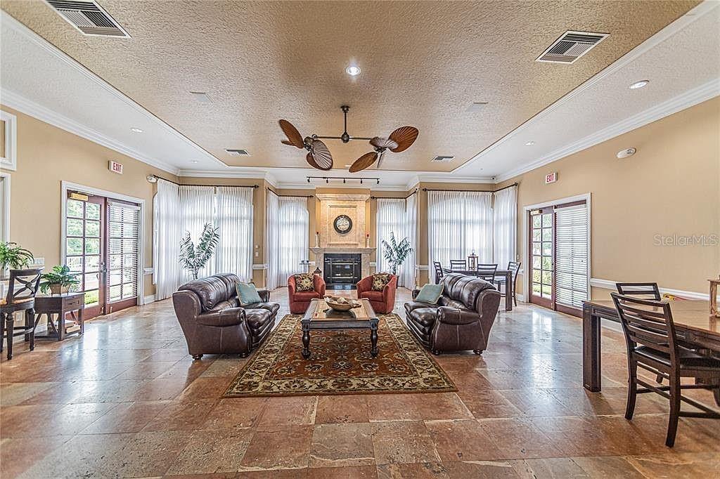 A spacious living area features a fireplace, leather furniture, tile flooring, and a ceiling fan — 420 SUMMIT RIDGE PLACE UNIT 204, LONGWOOD, FL