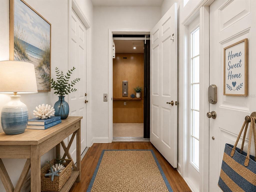 A hallway with wood flooring, a console table, and an open door revealing an elevator — 1338 EMERALD DUNES DRIVE UNIT 35, SUN CITY CENTER, FL