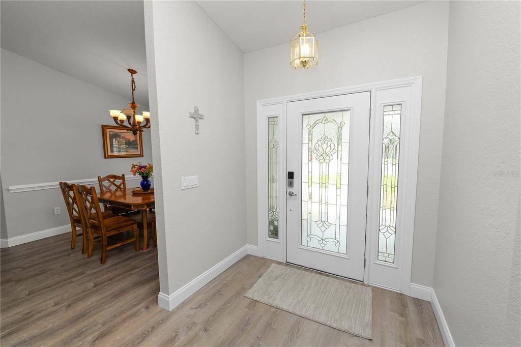An entryway with a white front door, wood-look flooring, and a view into a dining room — 1564 NORWICK WAY, LAKELAND, FL