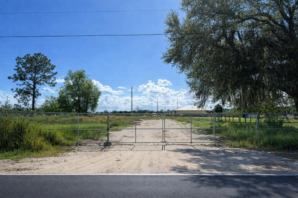 A fenced, dirt-covered vacant lot sits behind a gate next to a large tree — MARICAMP RD, OCALA, FL