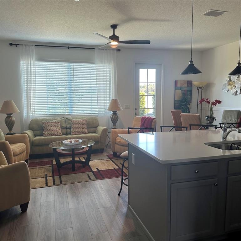 A living room with a sofa and chairs sits adjacent to a kitchen island — 801 BENOI DRIVE, DAVENPORT, FL
