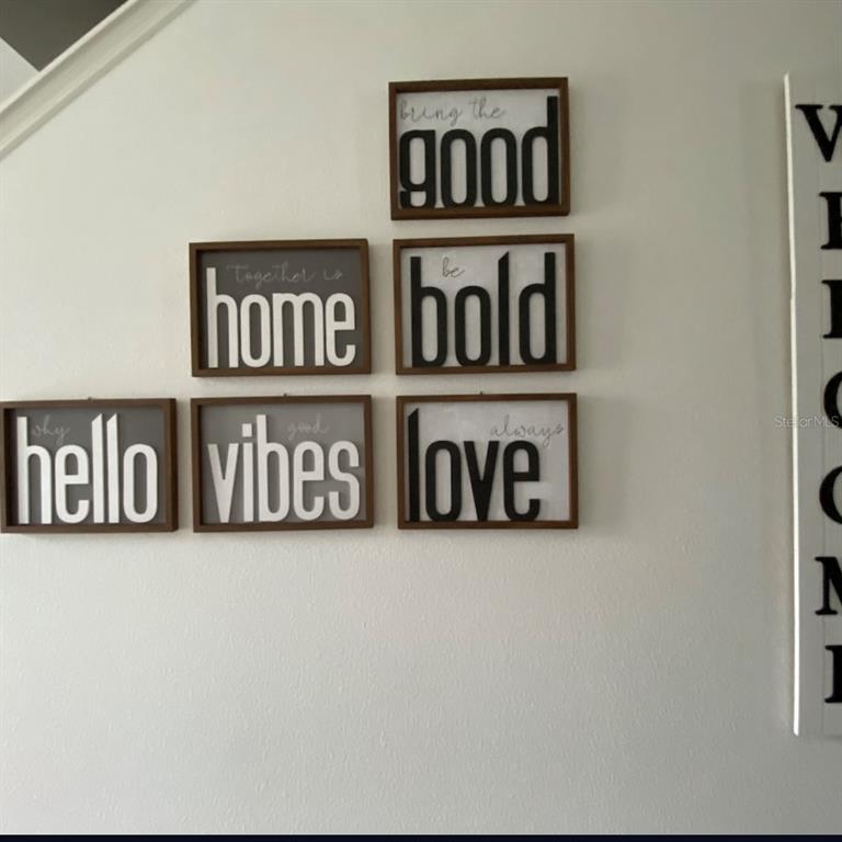 A wall displays a gallery arrangement of six framed signs with inspirational text — 801 BENOI DRIVE, DAVENPORT, FL