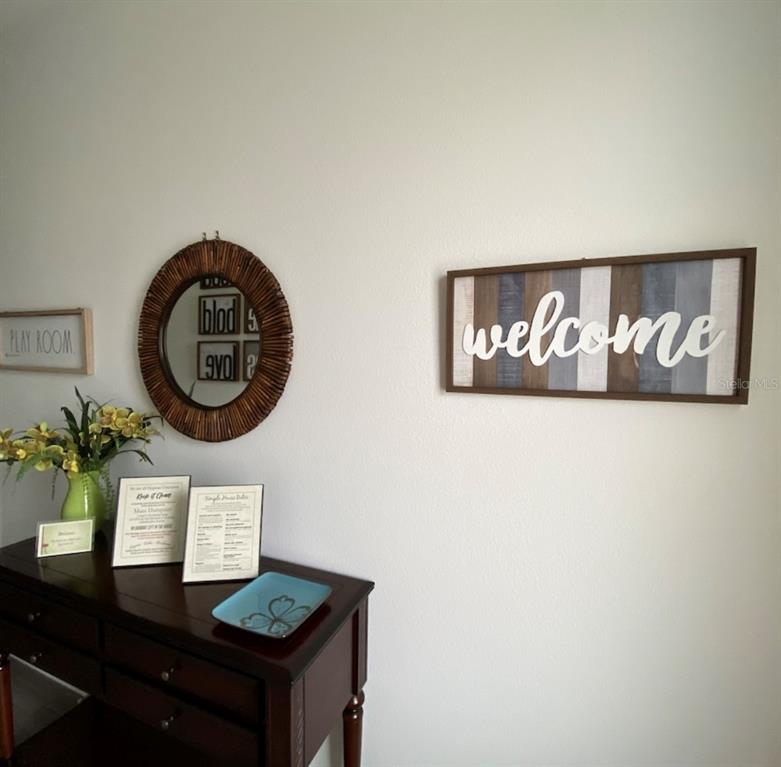 A wooden console table sits against a white wall decorated with a mirror and signs — 801 BENOI DRIVE, DAVENPORT, FL