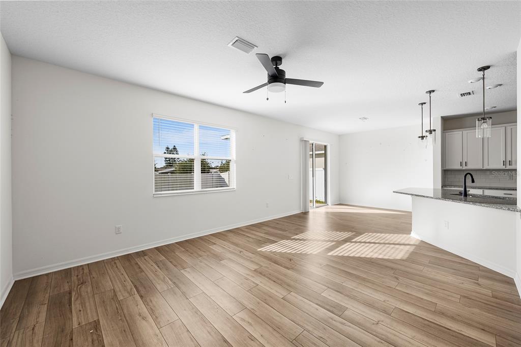 An open-concept living area features light wood-look flooring, a ceiling fan, and a kitchen island — 2854 89TH STREET CIRCLE E, PALMETTO, FL