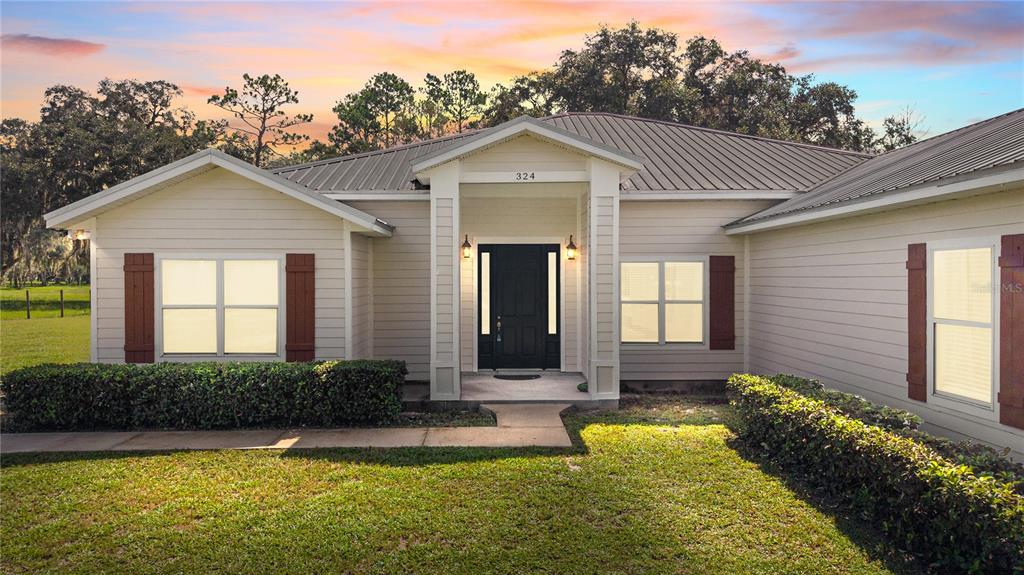 A single-story house with light siding, a metal roof, and a dark front door — 324 NE 300TH STREET, CROSS CITY, FL