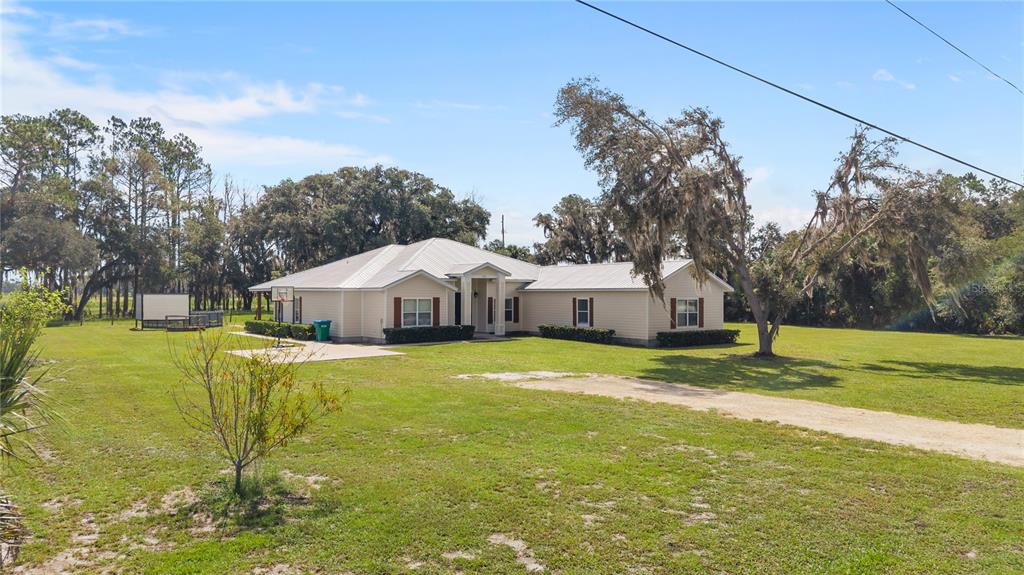 A single-story house with light-colored siding and a metal roof sits on a grassy lot — 324 NE 300TH STREET, CROSS CITY, FL