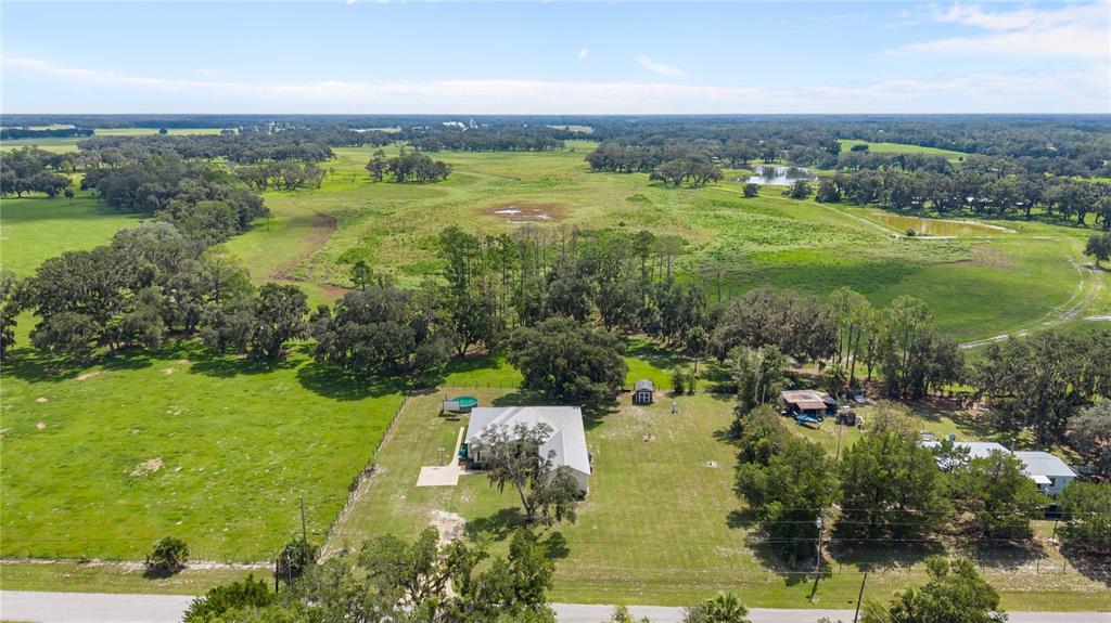 An aerial view shows a house with a metal roof surrounded by green pastures — 324 NE 300TH STREET, CROSS CITY, FL