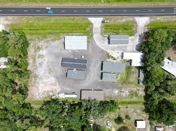 An aerial view shows several buildings on a gravel lot adjacent to a highway — 25164 E COLONIAL DRIVE, CHRISTMAS, FL