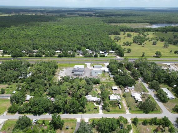An aerial view shows a commercial property with several buildings surrounded by trees and roads — 25164 E COLONIAL DRIVE, CHRISTMAS, FL