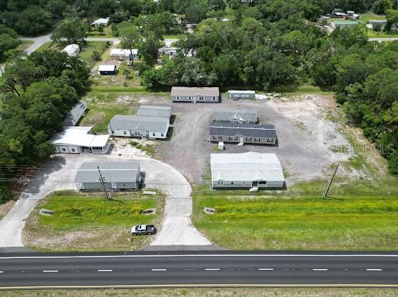 An aerial view shows several manufactured homes on a gravel lot next to a highway — 25164 E COLONIAL DRIVE, CHRISTMAS, FL