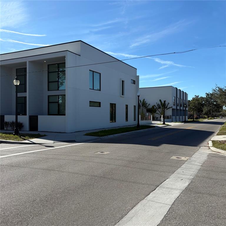A modern white multi-unit building stands on a street corner under a clear blue sky — 1744 10TH STREET, SARASOTA, FL