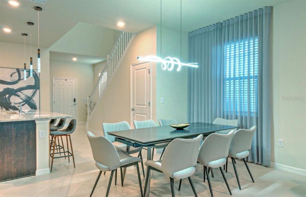 A dining area features a dark rectangular table, six light-colored chairs, and modern pendant lighting — 16231 TRINIDAD WAY, CLERMONT, FL