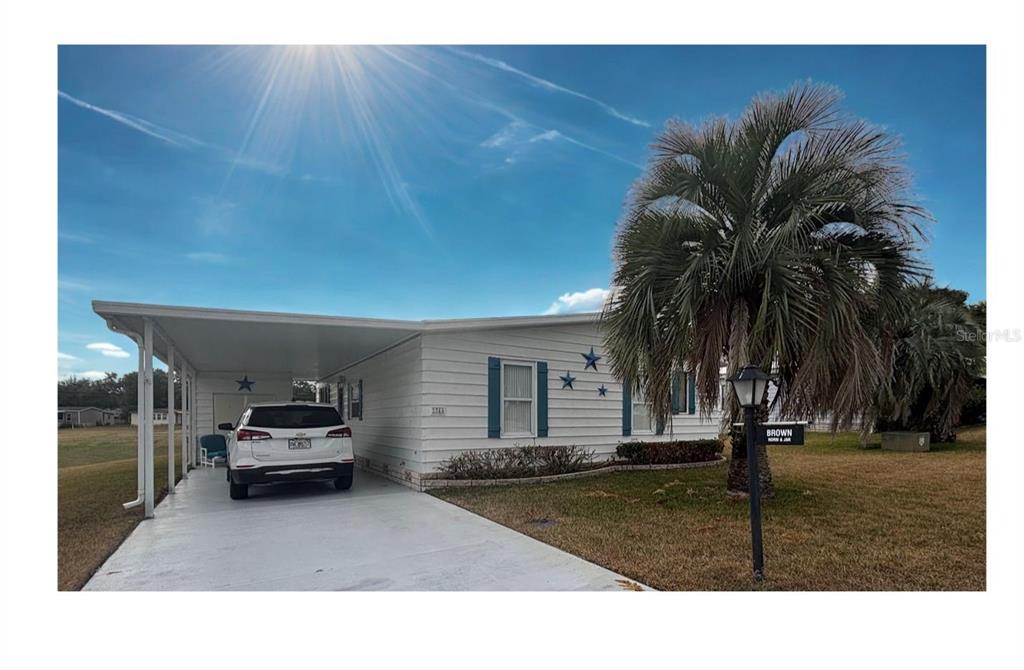 A white mobile home with blue shutters and decorative stars sits behind a palm tree — 3746 PARWAY ROAD UNIT 1349, ZELLWOOD, FL