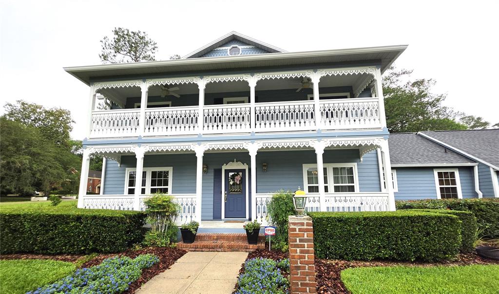 A two-story blue house features a wrap-around porch with white decorative railings and trim — 4326 SW 80TH STREET, GAINESVILLE, FL