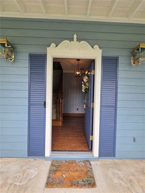 A front door with a decorative pediment opens into a foyer with wood-look flooring — 4326 SW 80TH STREET, GAINESVILLE, FL