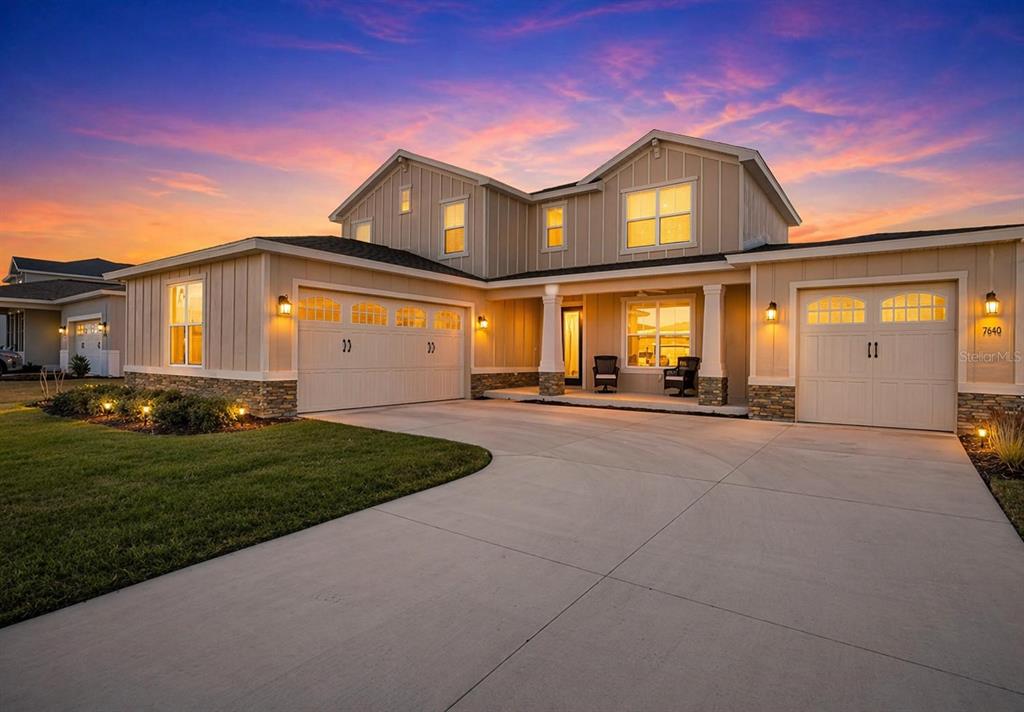 A two-story suburban house with a beige exterior, stone accents, and a concrete driveway — 7610 SW 60TH STREET, OCALA, FL