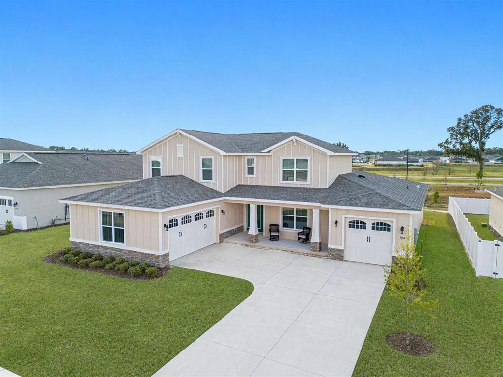 A two-story house with beige vertical siding, a stone base, and a three-car garage — 7610 SW 60TH STREET, OCALA, FL
