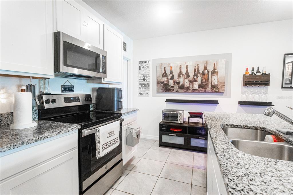 A kitchen with white cabinets, granite countertops, stainless steel appliances, and tile flooring — 643 BELGROVE STREET, DEBARY, FL