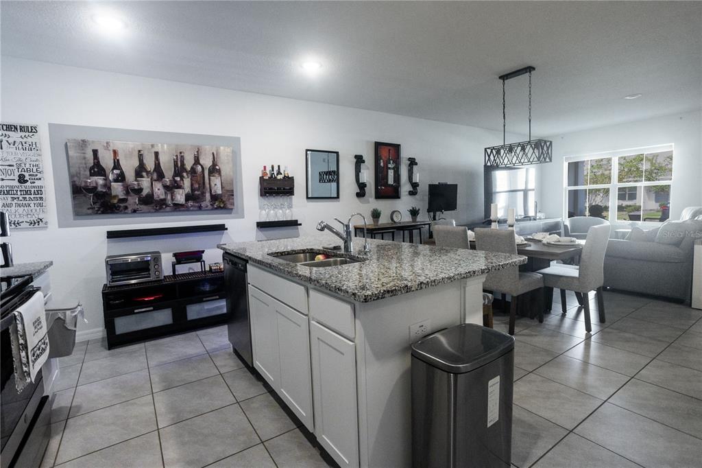 A kitchen with a granite-topped island, white cabinets, and an adjacent dining area — 643 BELGROVE STREET, DEBARY, FL