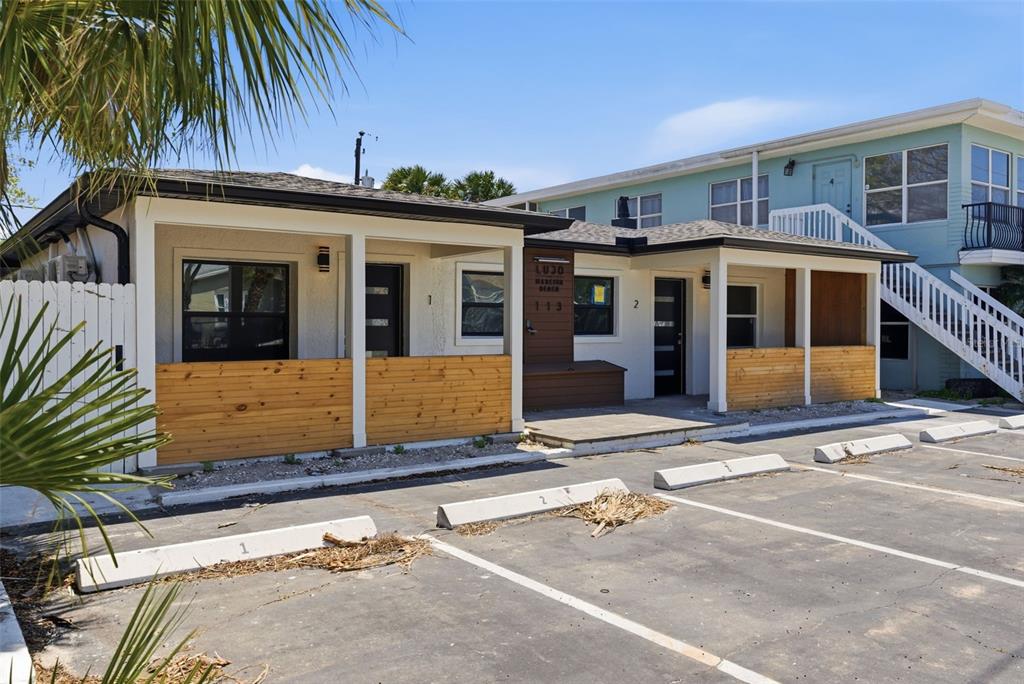 A single-story building with two numbered units features wood-paneled porches and a paved parking lot — 113 145TH AVENUE E UNIT 3, MADEIRA BEACH, FL