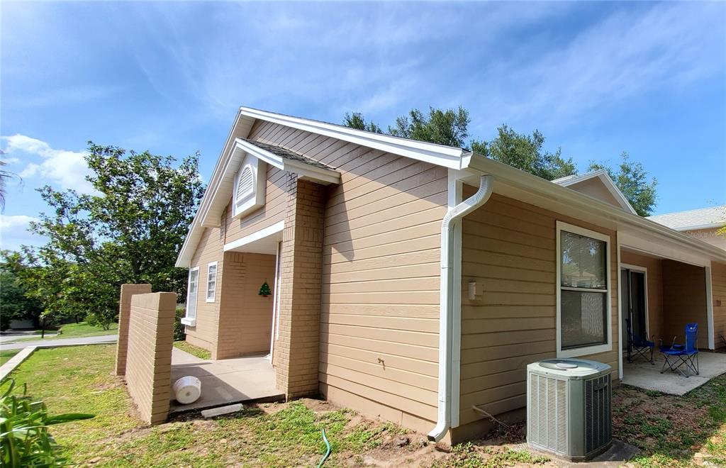 A tan house exterior features horizontal siding, a brick accent wall, and a concrete patio — 239 ALSTON DRIVE, ORLANDO, FL