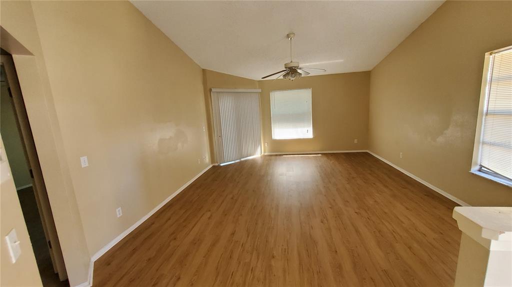 An empty living room with light wood-look flooring, beige walls, and a ceiling fan — 239 ALSTON DRIVE, ORLANDO, FL