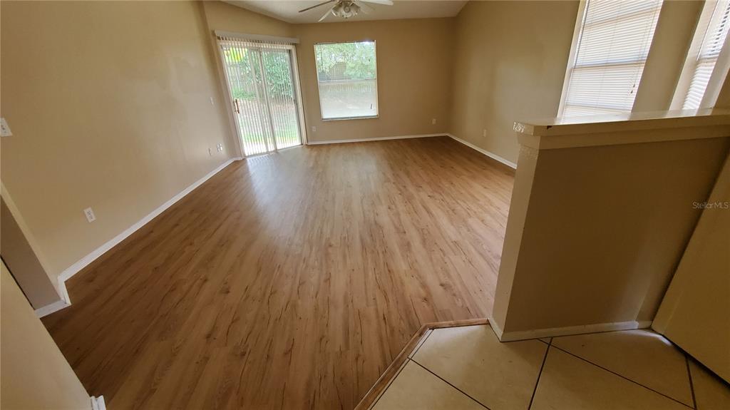An empty living room features wood-look flooring, a sliding glass door, and a half wall — 239 ALSTON DRIVE, ORLANDO, FL