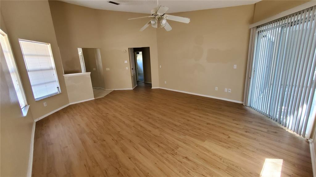 An empty living room with light wood-look flooring, beige walls, and a ceiling fan — 239 ALSTON DRIVE, ORLANDO, FL