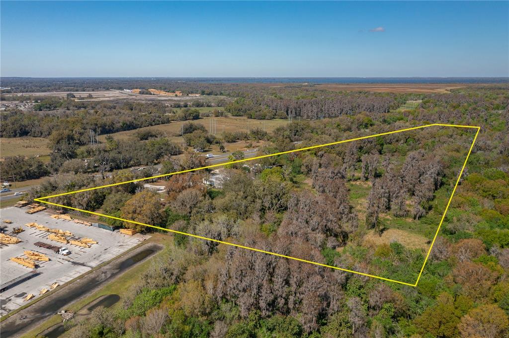 An aerial view shows a large, wooded triangular plot of land outlined in yellow — 1800 US HIGHWAY 17 N, BARTOW, FL